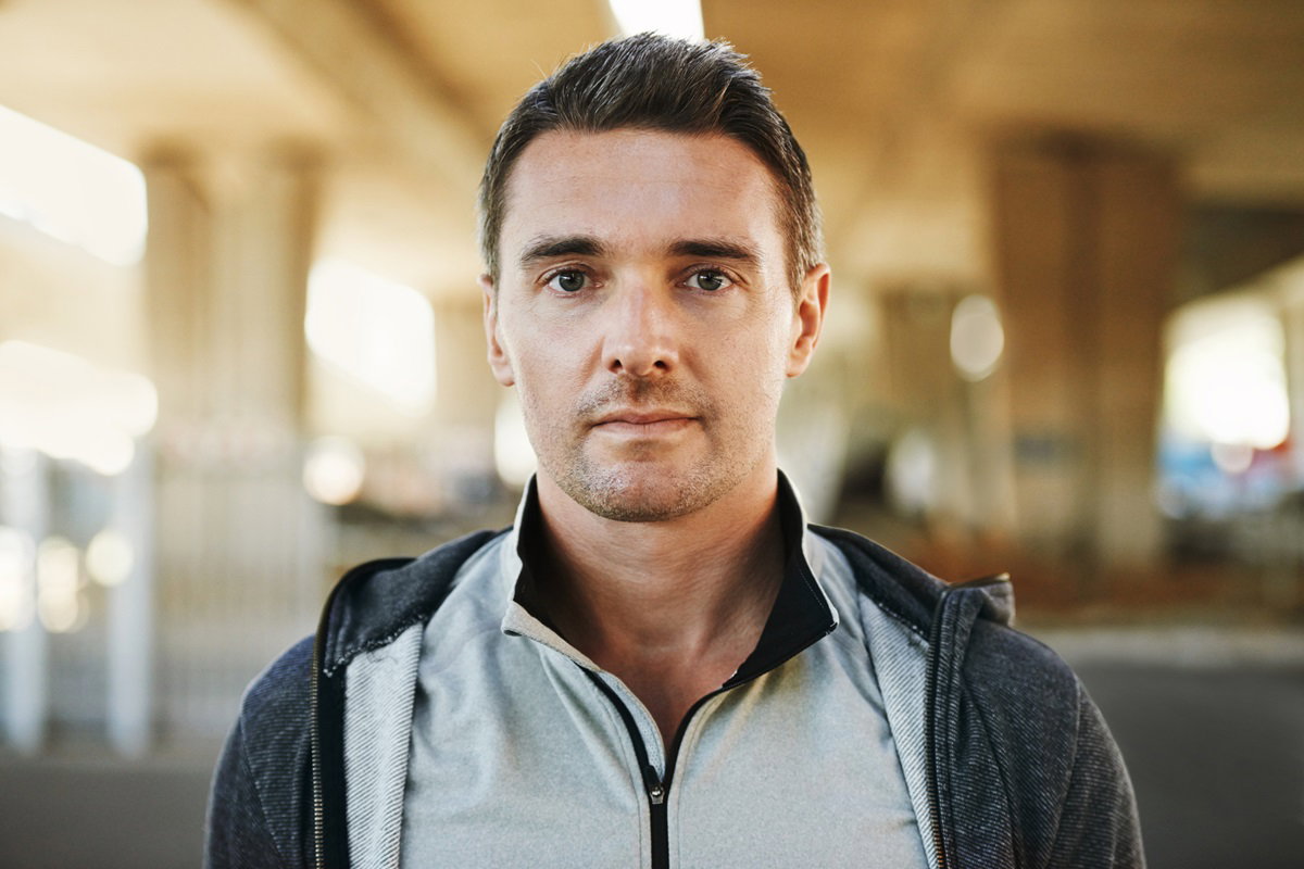 przystojny mężczyzna w bluzie w średnim wieku stoi i patrzy poważnym wzrokiem przed siebie