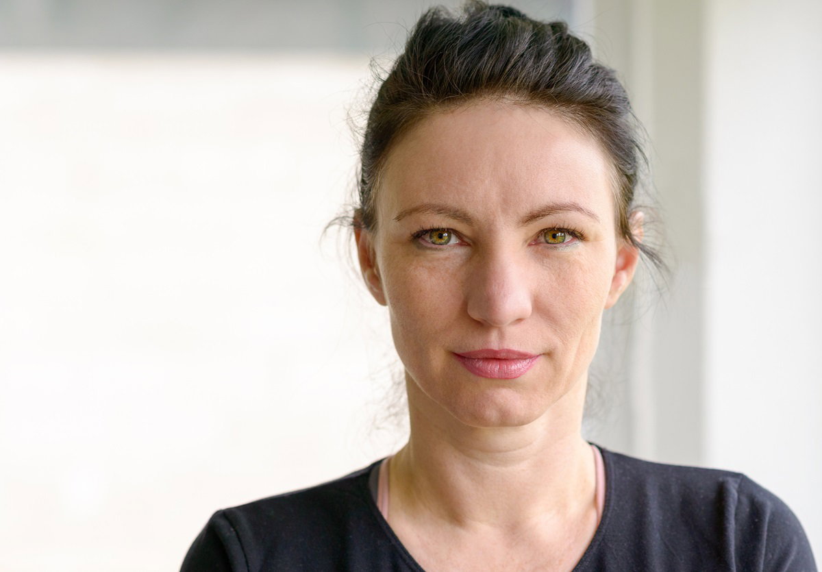 młoda kobieta ze spiętymi włosami stoi i patrzy przed siebie z nadzieją w oczach