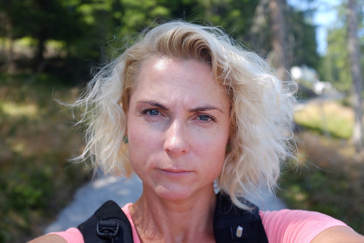 kobieta w średnim wieku z blond włosami robi sobie selfie będąc na wakacjach i patrzy poważnym wzrokiem