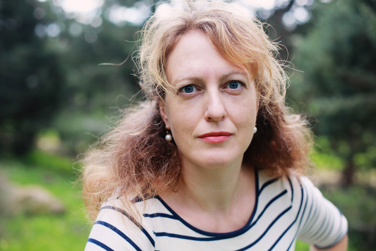 kobieta w dojrzałym wieku w bluzce w paski stoi na dworze i patrzy przed siebie przestraszonym wzrokiem