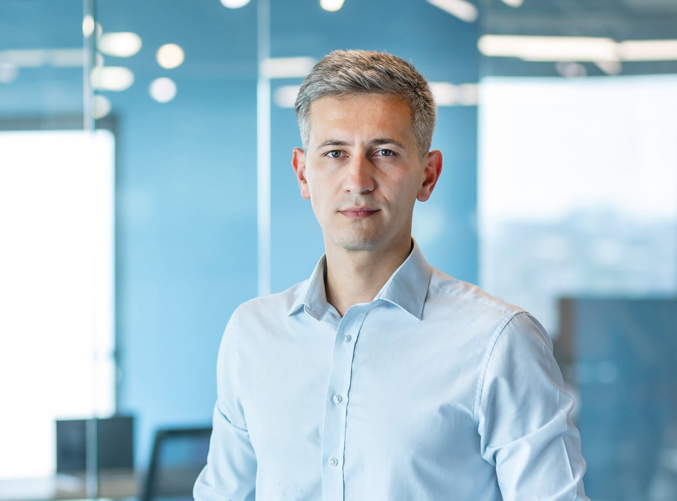 młody mężczyzna w koszuli stoi w biurze i patrzy przed siebie z poważną miną