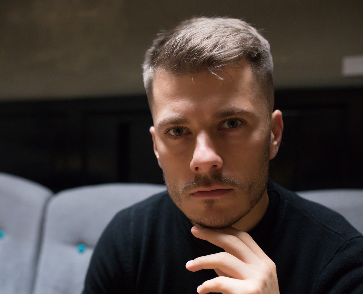 młody mężczyzna w czarnym swetrze patrzy przed siebie smutnym wzrokiem