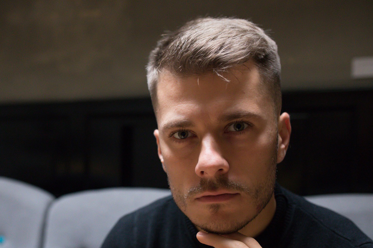młody mężczyzna w czarnym swetrze patrzy przed siebie smutnym wzrokiem