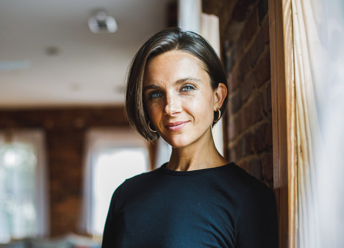 młoda dziewczyna z ciemnymi włosami na pazia stoi w salonie i lekko się uśmiecha