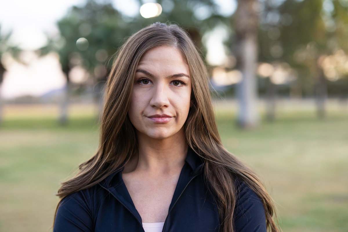 młoda dziewczyna w czarnej bluzie i z długimi włosami stoi na zewnątrz i ma sceptyczną minę