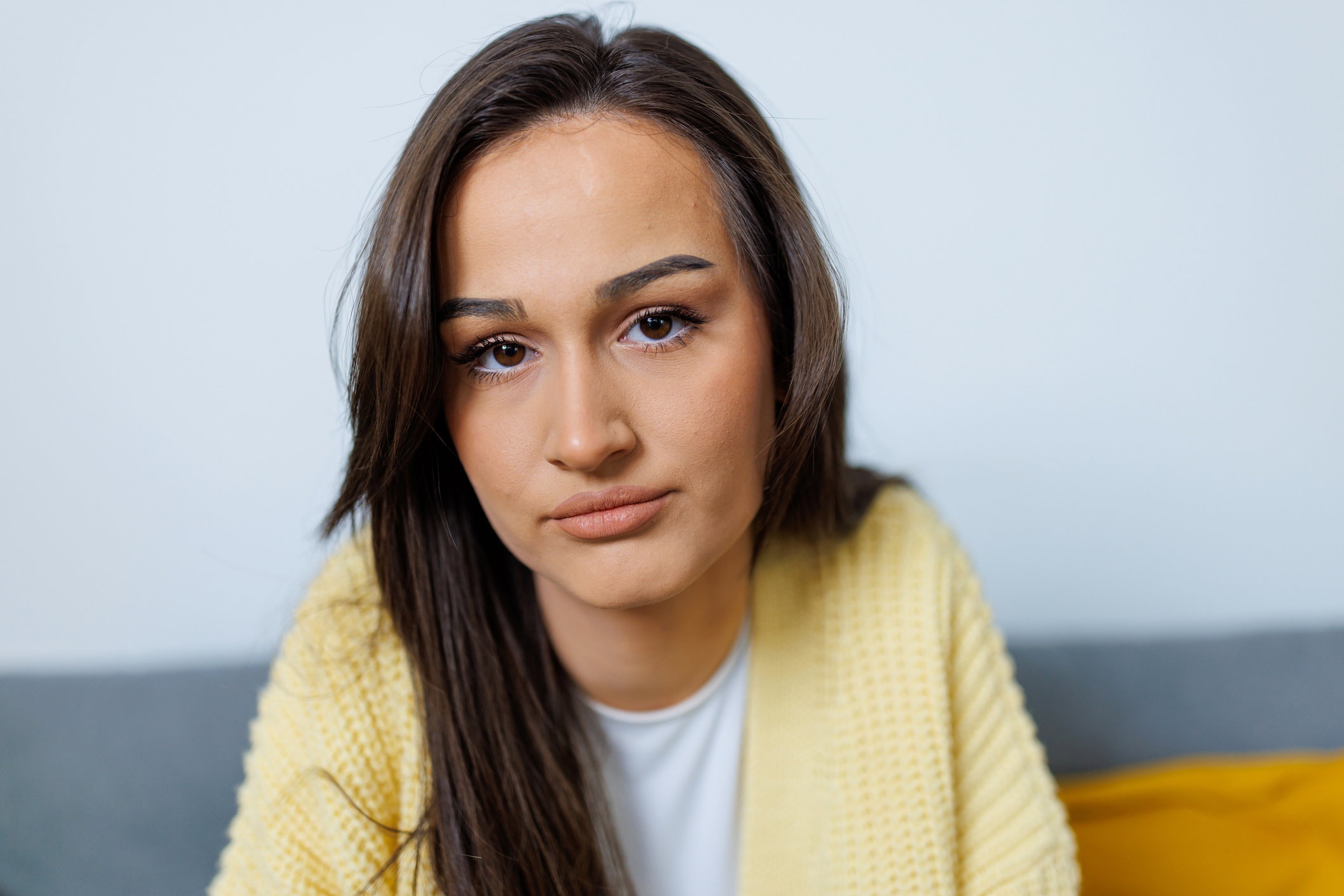 Close-up of a young woman looking at the camera with a sad and depressed look on her face