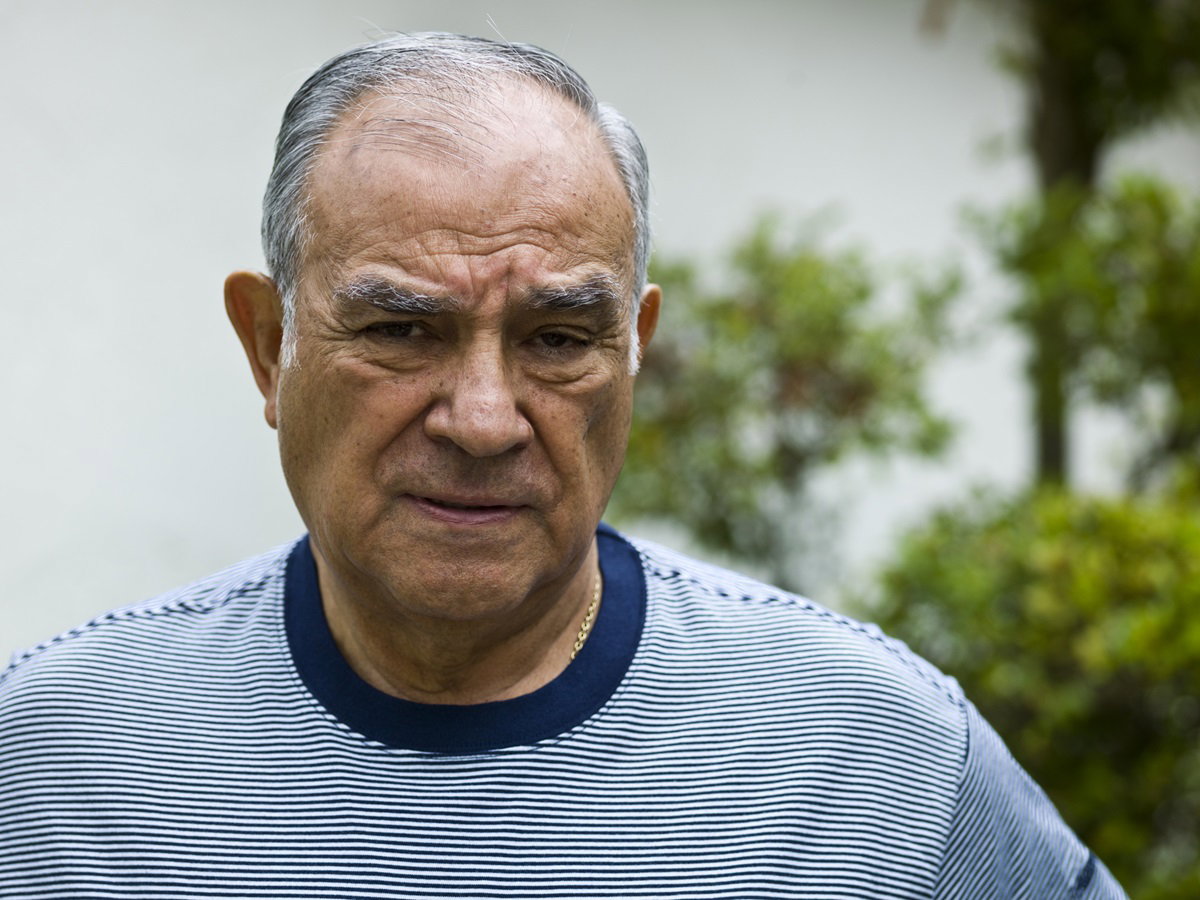 mężczyzna w senioralnym wieku 70+ z siwymi włosami w t-shircie w prążki z kwaśną miną