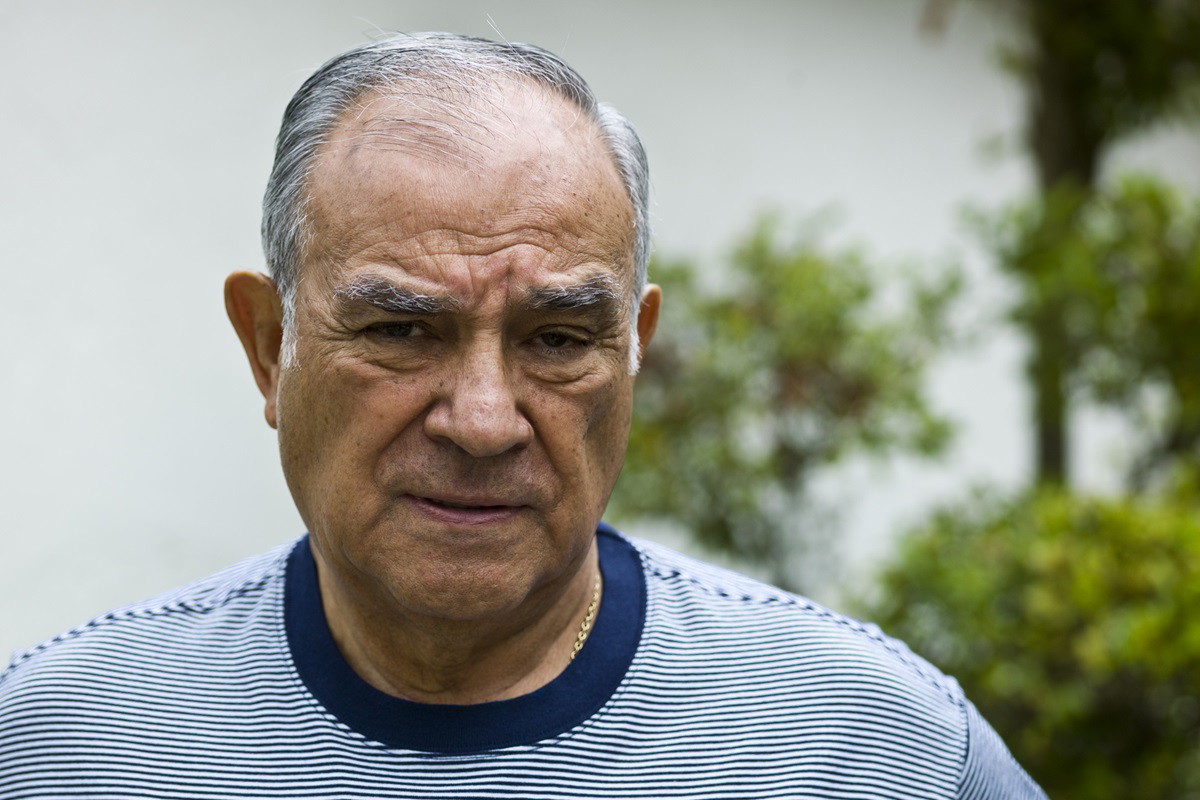 mężczyzna w senioralnym wieku 70+ z siwymi włosami w t-shircie w prążki z kwaśną miną