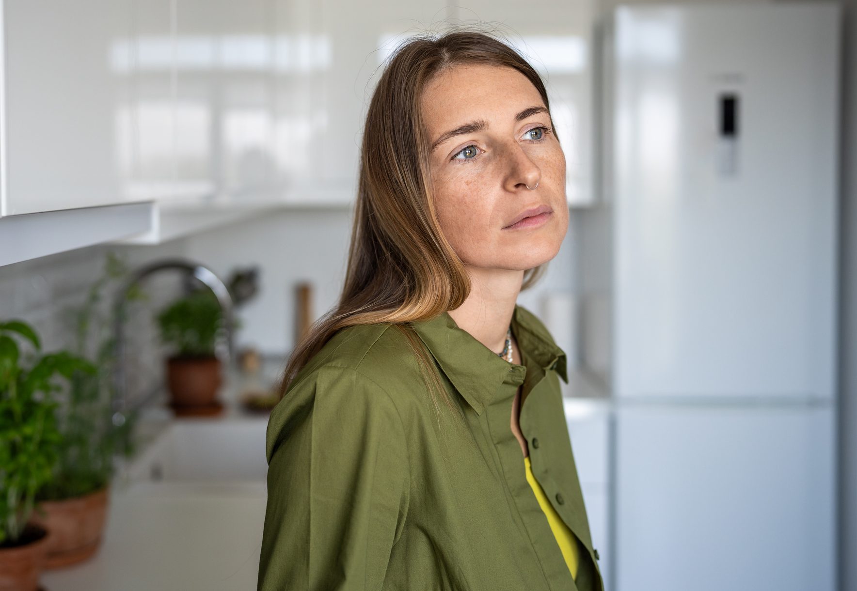Pensive serious thoughtful middle aged woman sadly looking has bad mood standing on kitchen at home.