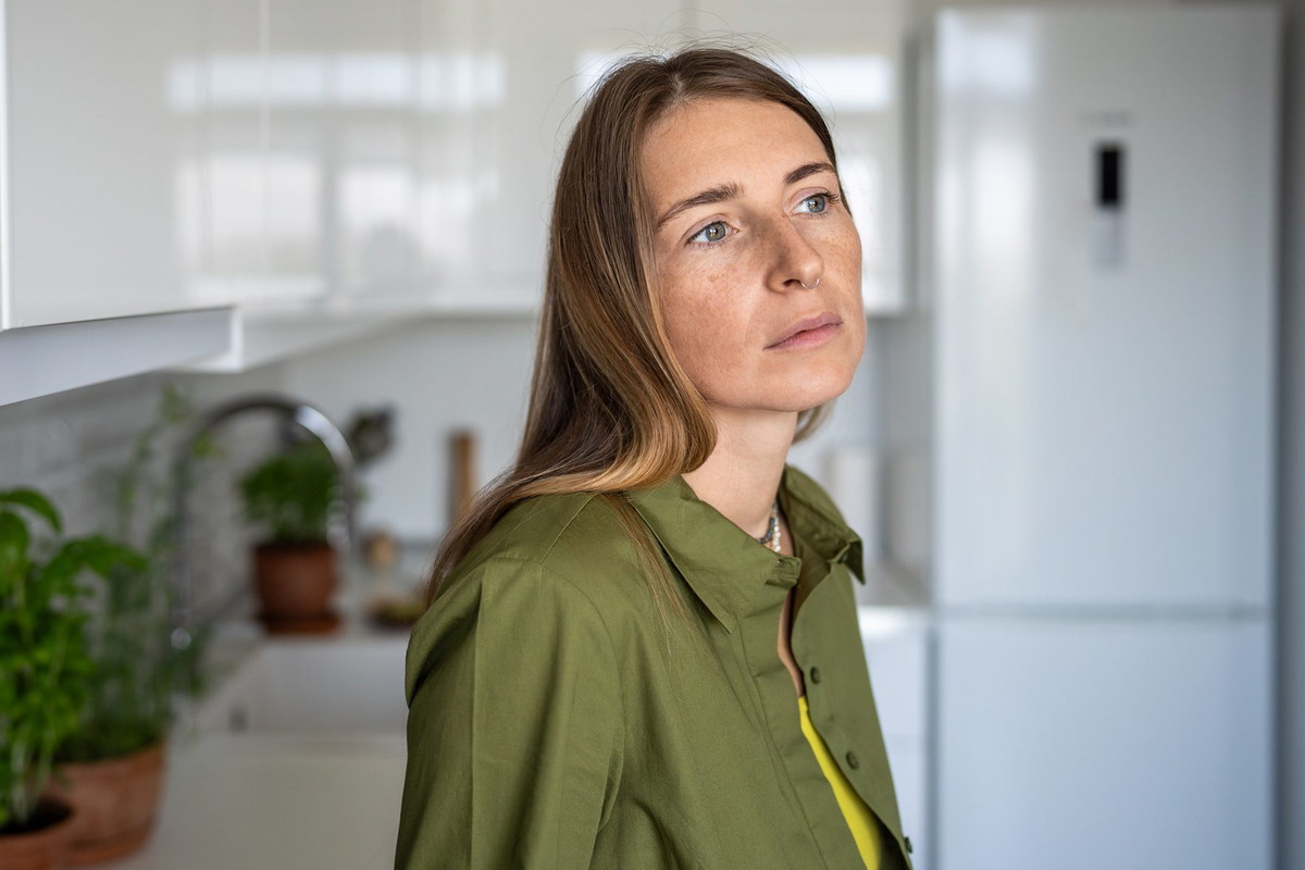 Pensive serious thoughtful middle aged woman sadly looking has bad mood standing on kitchen at home.