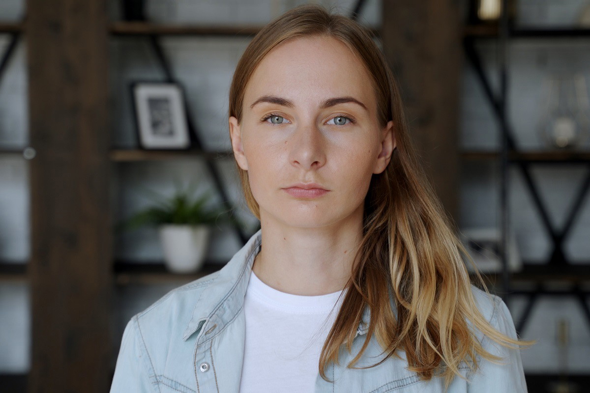 młoda dziewczyna z długimi włosami ciemny blond stoi w salonie i ma poważną minę