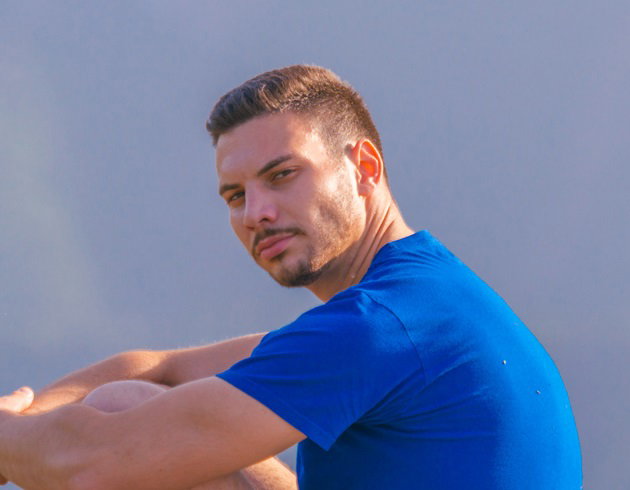 młody mężczyzna w niebieskim t-shircie siedzi w pięknych okolicznościach przyrody i patrzy zamyślony