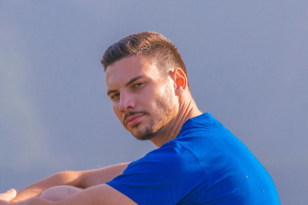 młody mężczyzna w niebieskim t-shircie siedzi w pięknych okolicznościach przyrody i patrzy zamyślony