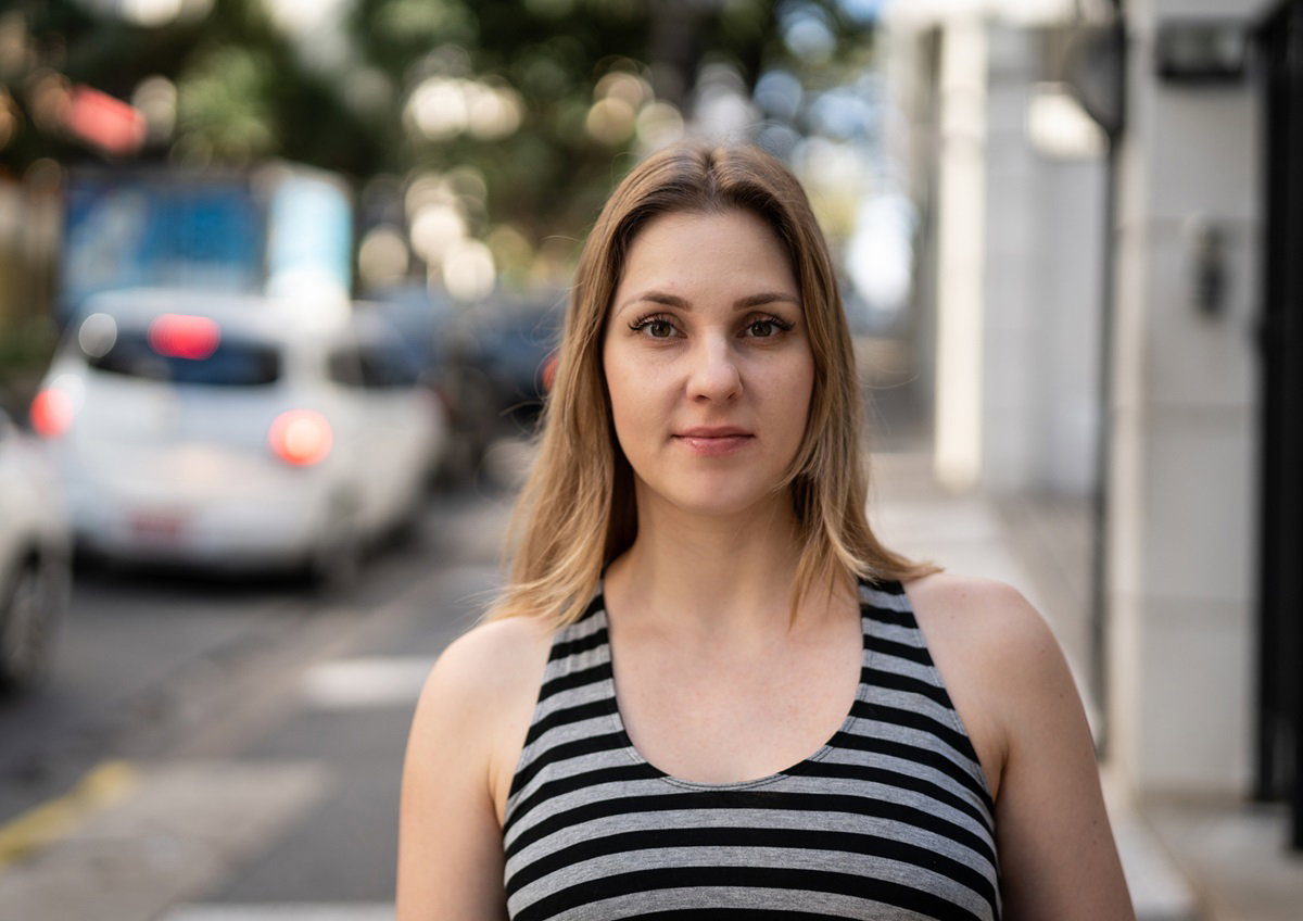 młoda kobieta z włosami ciemny blond i w topie w paski stoi na ulicy i patrzy zamyślona