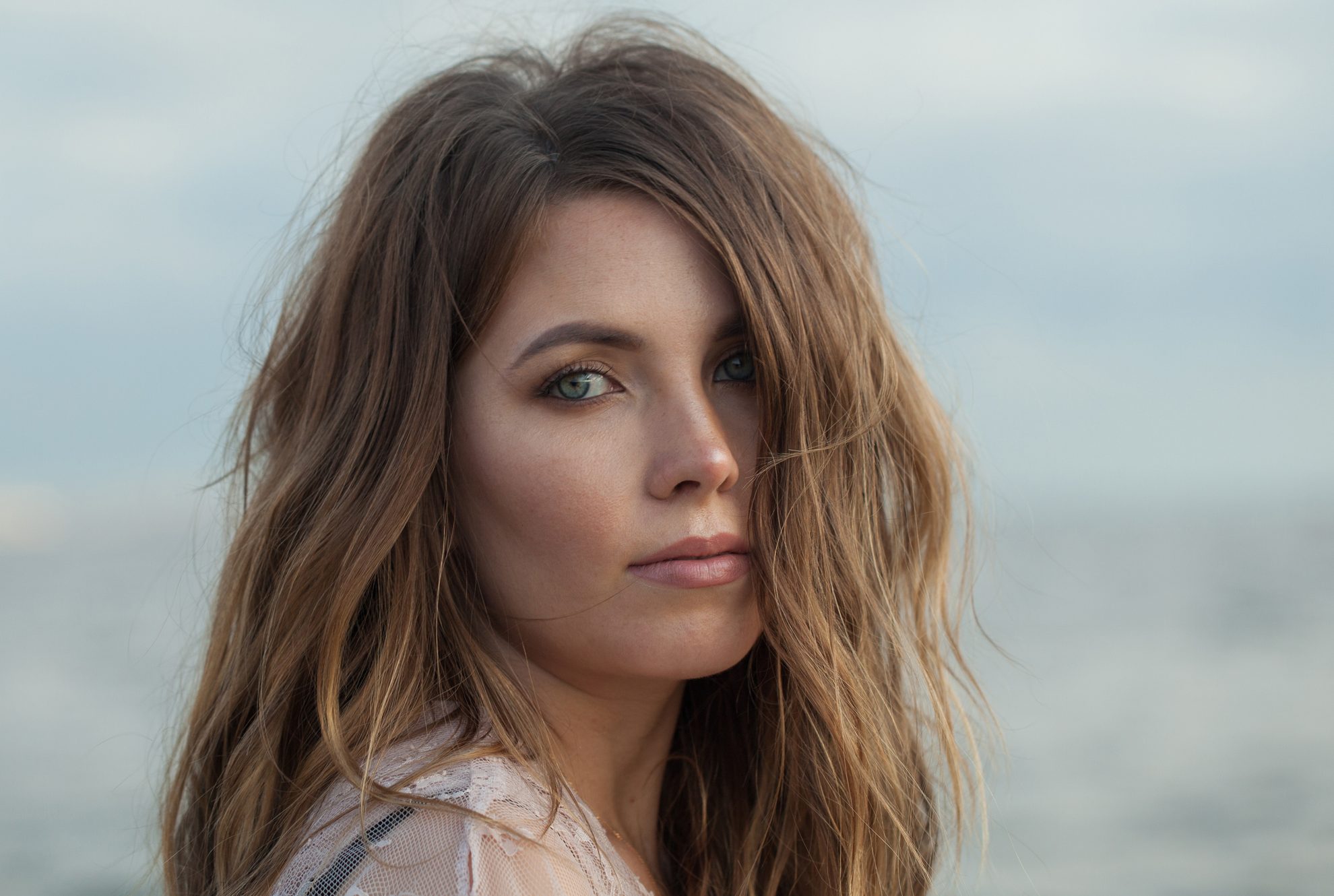 Fashionable young adult female model with windy brown hair walking outdoor
