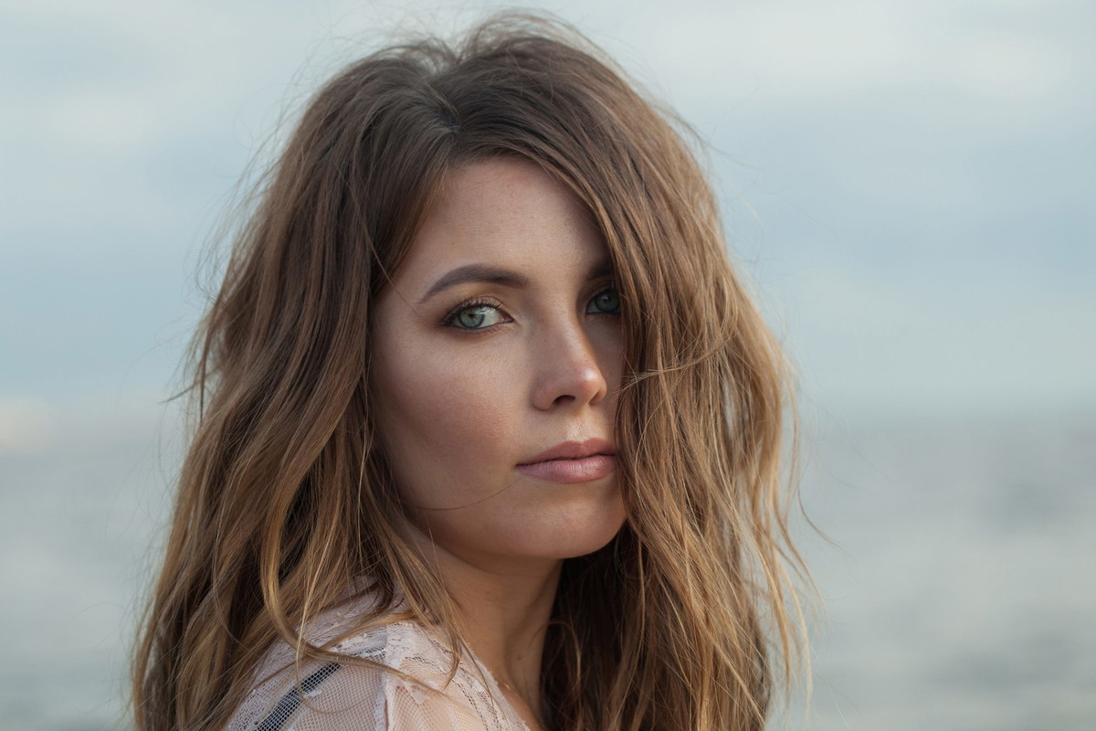 Fashionable young adult female model with windy brown hair walking outdoor
