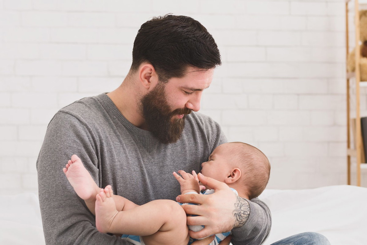 Father holding and soothing crying newborn baby in his arms
