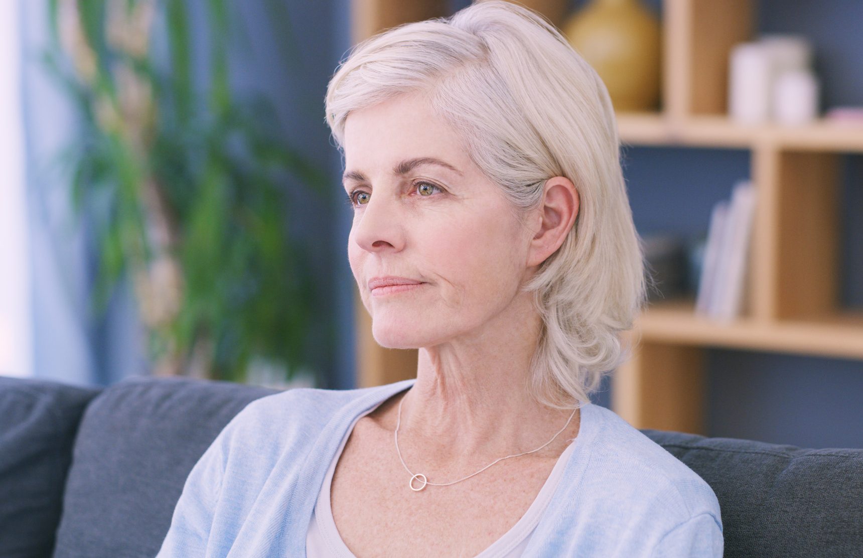 Shot of an older woman looking sad while lost in thought on the sofa at home