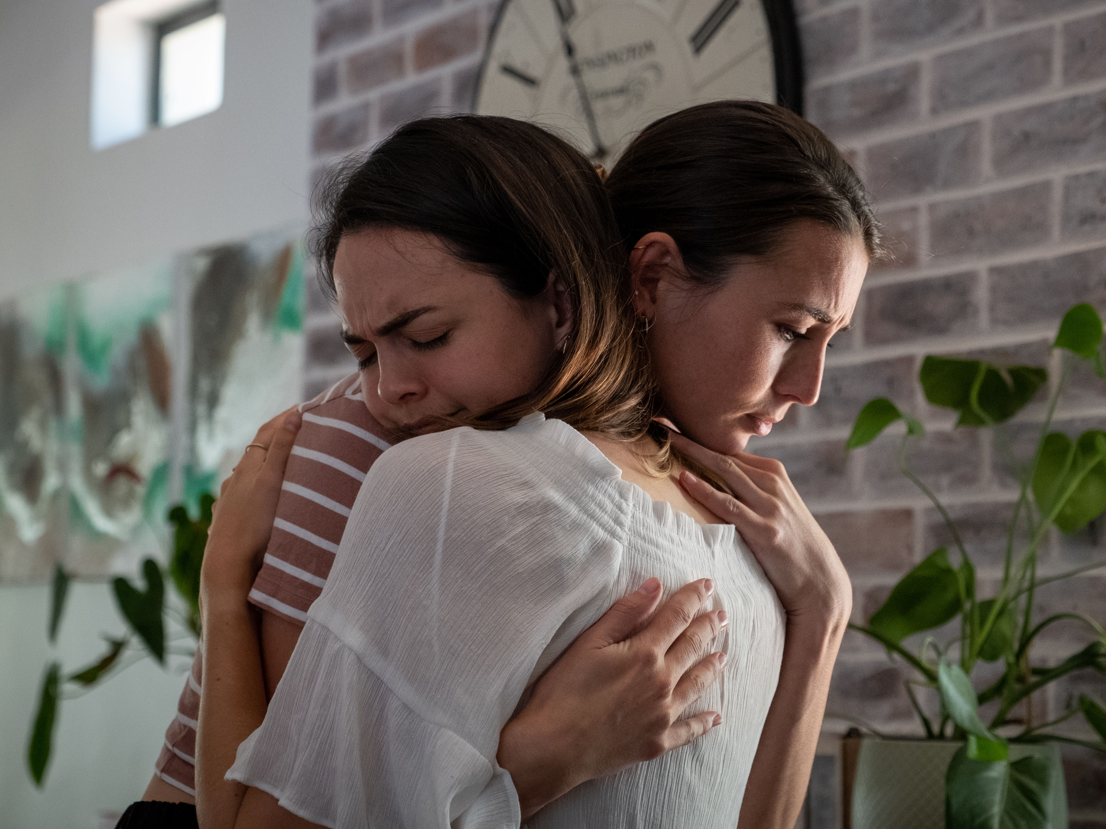Young woman embraces her emotional and distressed friend