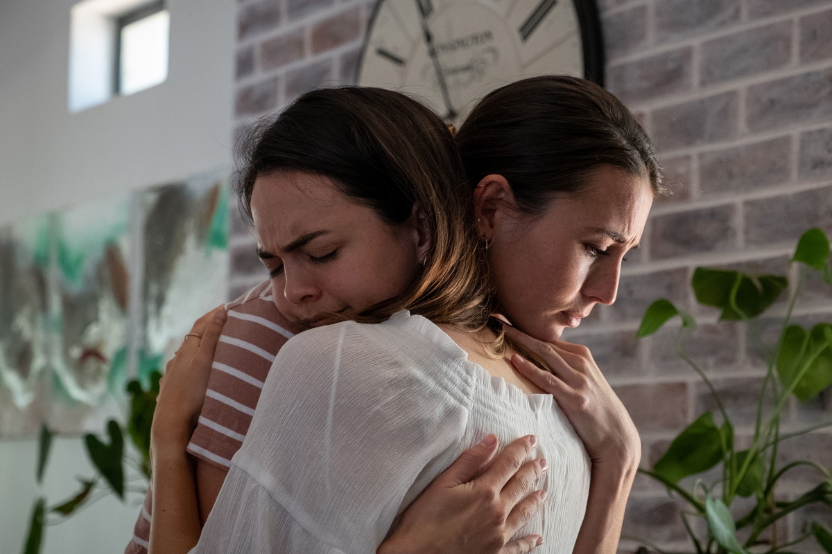 Young woman embraces her emotional and distressed friend