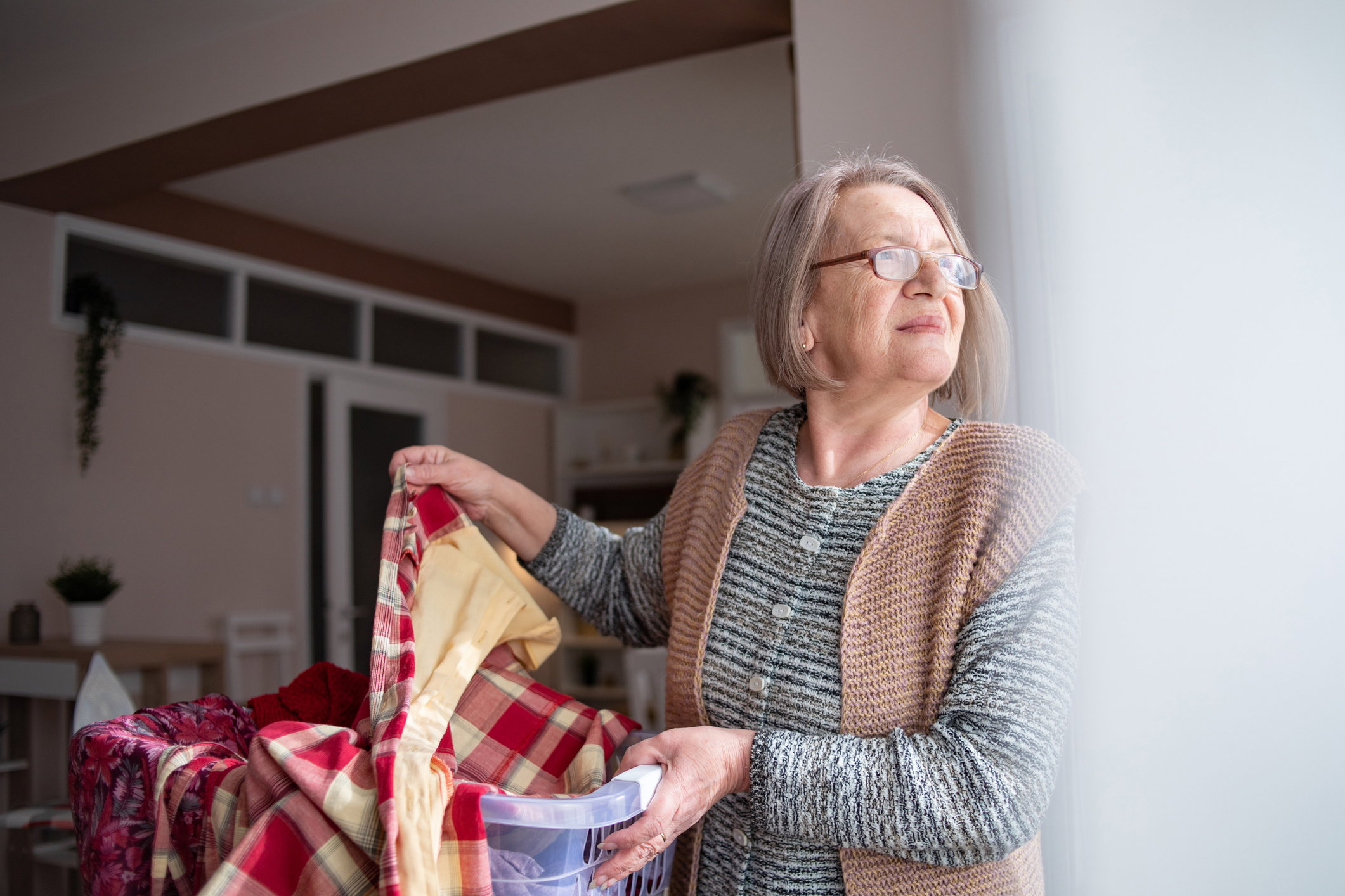 A mature older woman ironing clothes. Home chores. A portrait of an elderly mature woman who irons clothes and does everyday household chores - real ordinary people