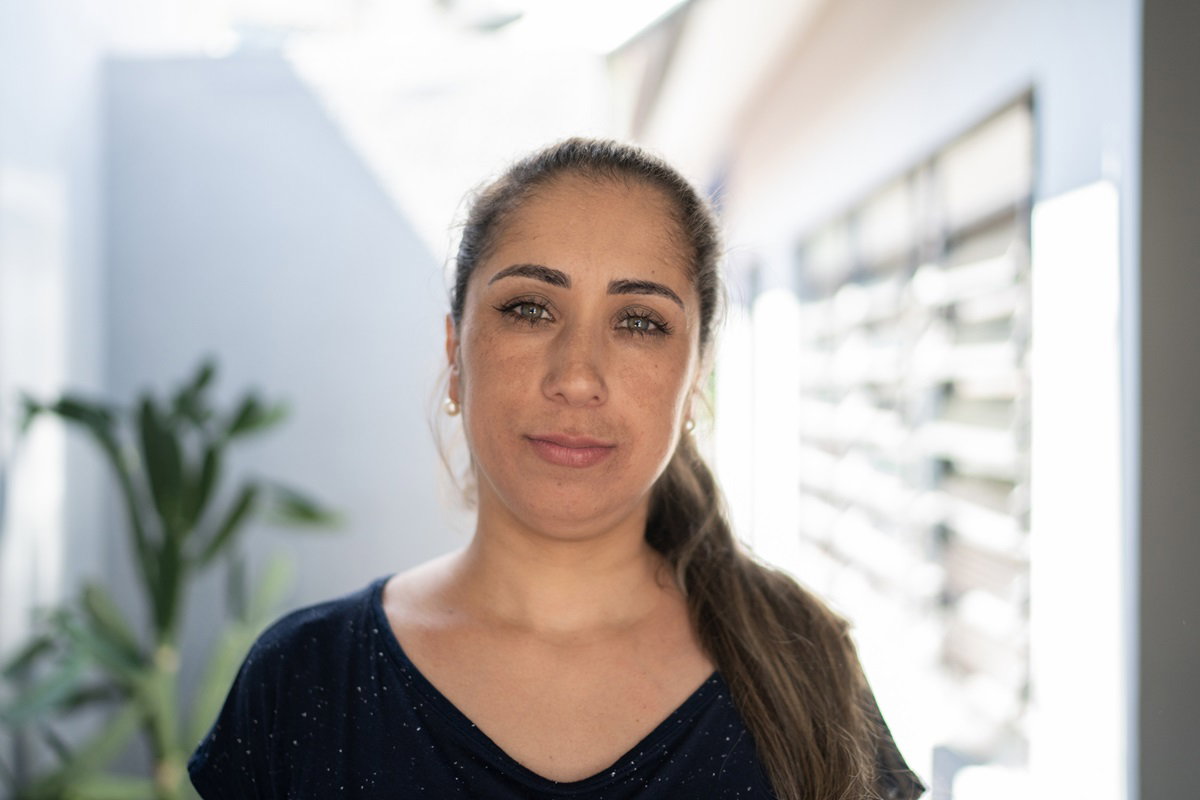 młoda kobieta w wieku około 30 lat z długimi włosami spiętymi w koński ogon siedzi w pokoju i patrzy z kpiącą miną