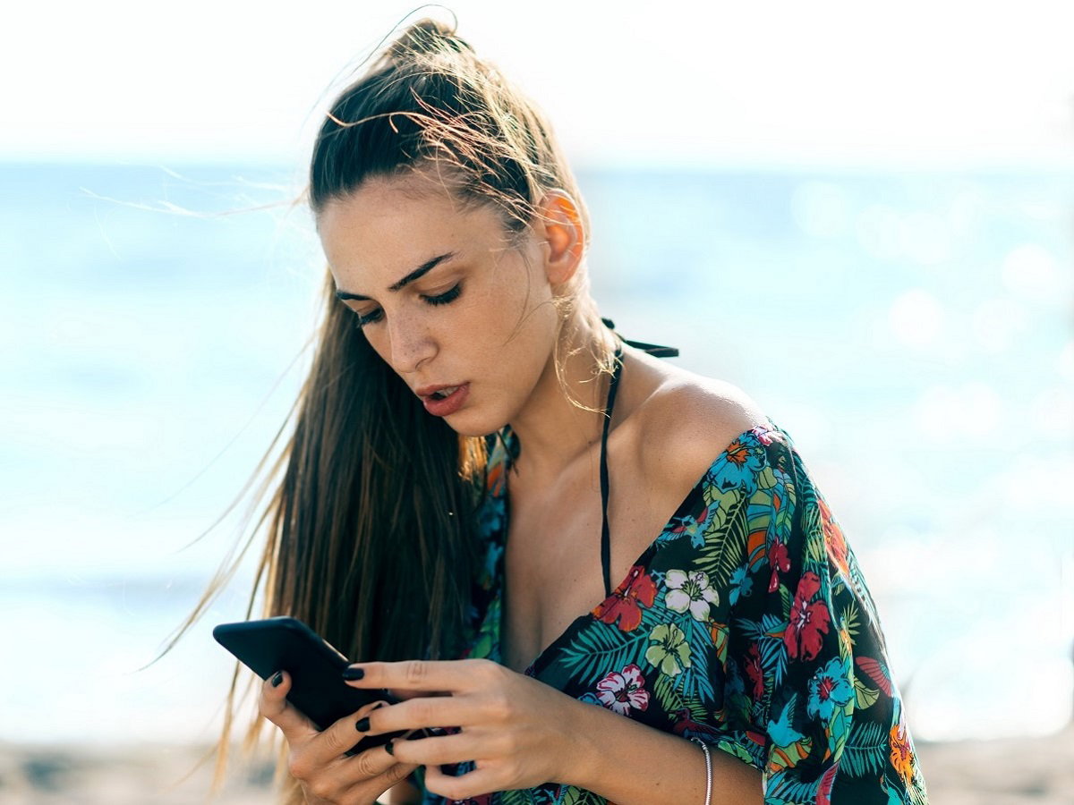 kobieta przeglądająca telefon na plaży