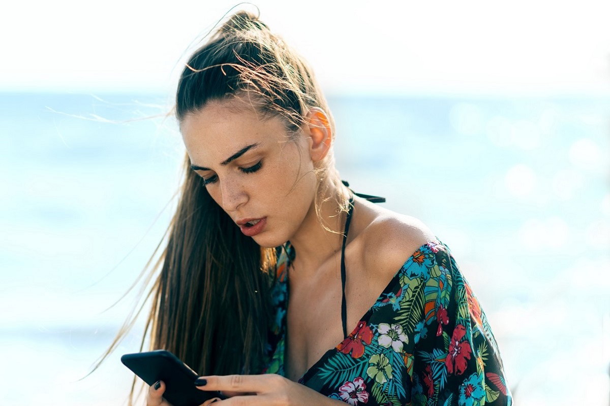kobieta przeglądająca telefon na plaży