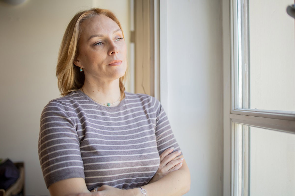 kobieta w wieku około 40 lat w bluzce w prążki blondynka patrzy w okno zamyślona