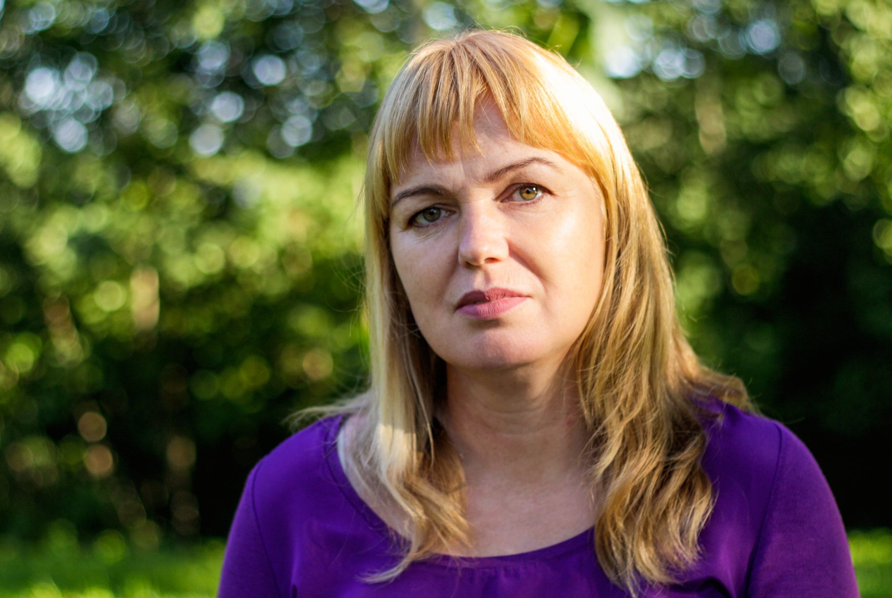 Serious Blonde Woman In Her 40S In Park. Mature Woman With Blonde Hair In Summer Park.