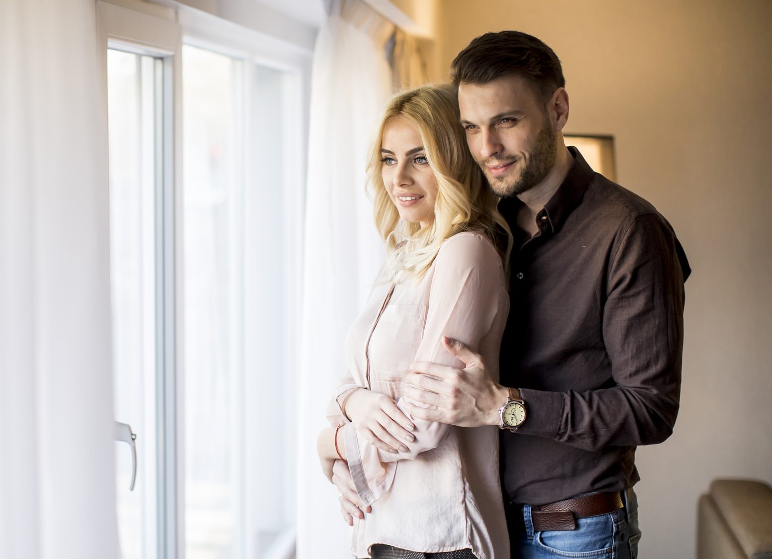Young couple standing by the window in the room