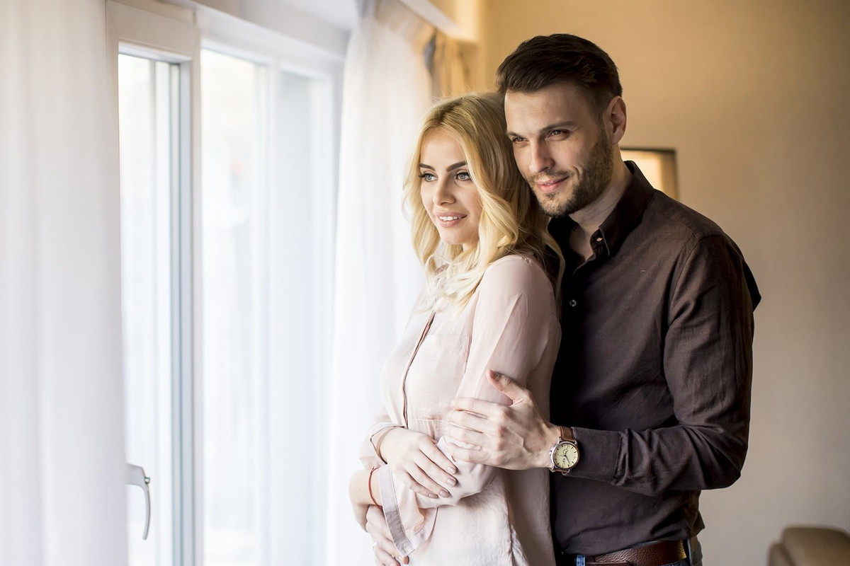 Young couple standing by the window in the room