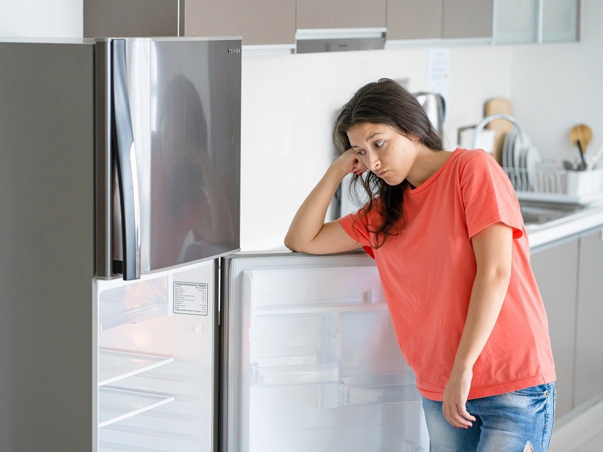 kobieta stojąca przy lodówce