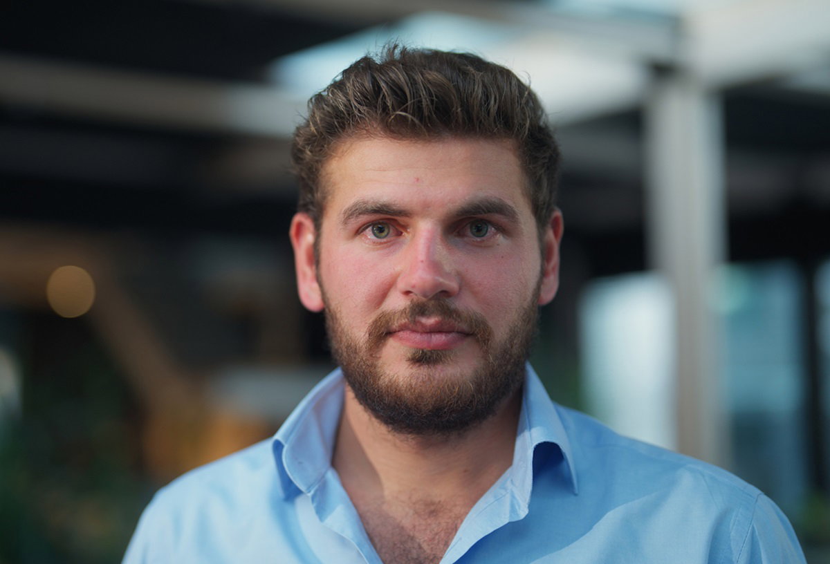 mężczyzna w wieku około 40 lat w jasnej koszuli i z jasnymi włosami i zarostem patrzy smutnym wzrokiem