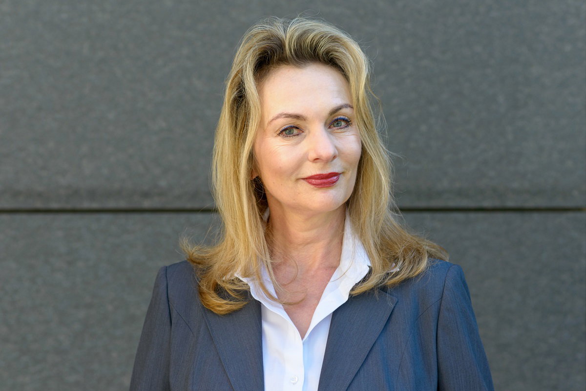 kobieta w wieku 50 plus elegancka stoi na tle ściany i się uśmiecha