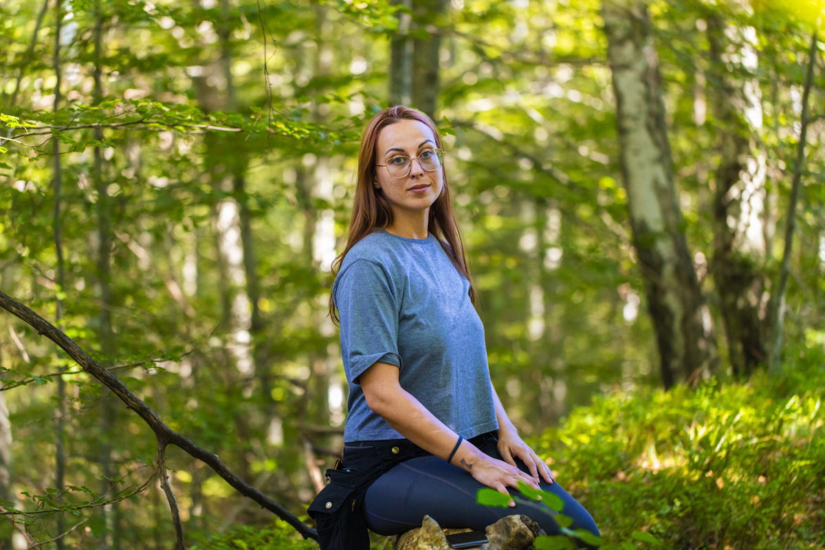 młoda kobieta w okularach w leśnej gęstwinie ze smutkiem w oczach