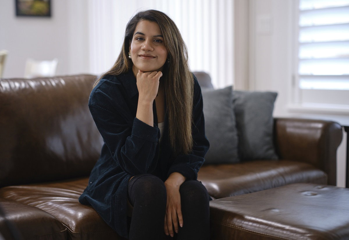 młoda kobieta w wieku około 30 plus z długimi włosami siedzi na skórzanej kanapie i się uśmiecha