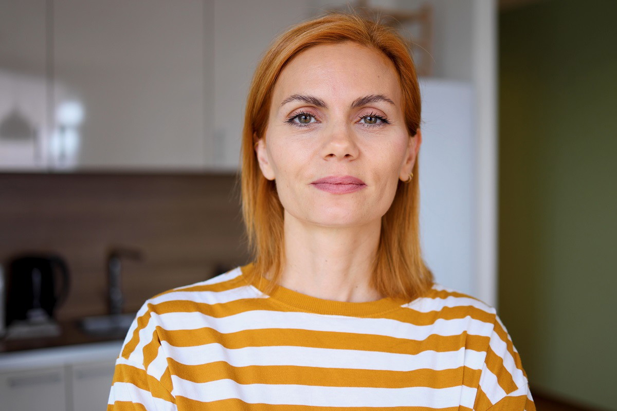 młoda kobieta z jasnopomarańczowymi włosami w pasiastym t-shircie stoi w kuchni i ma kpiącą minę