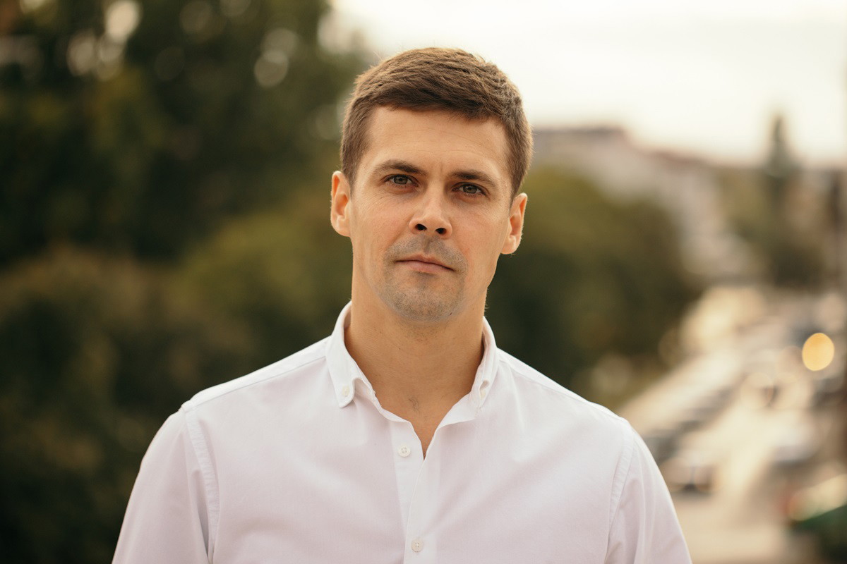 młody mężczyzna w białej koszuli stoi na tle miasta zmartwiony