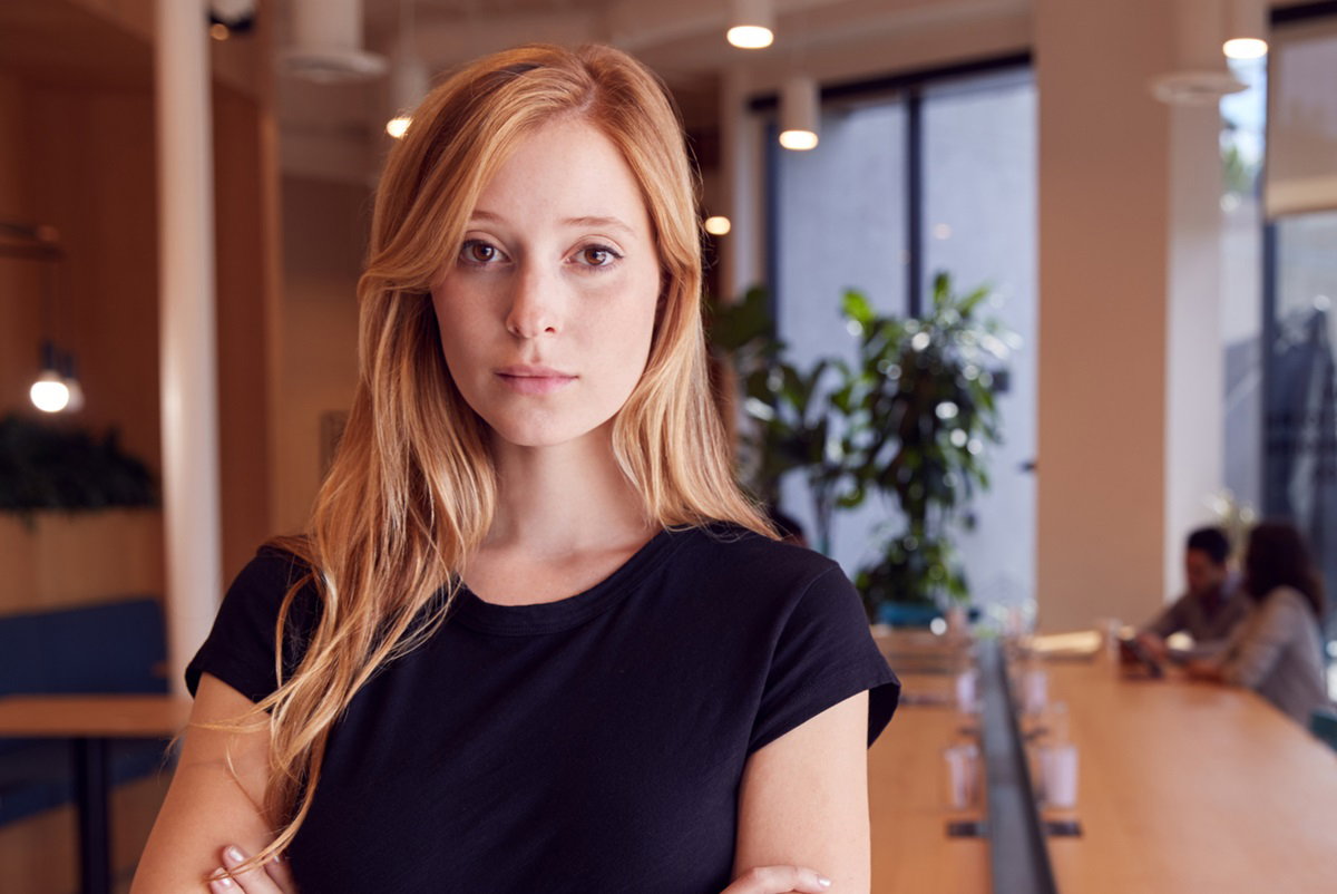 młoda kobieta z długimi włosami stoi w biurze ze smutnym spojrzeniem