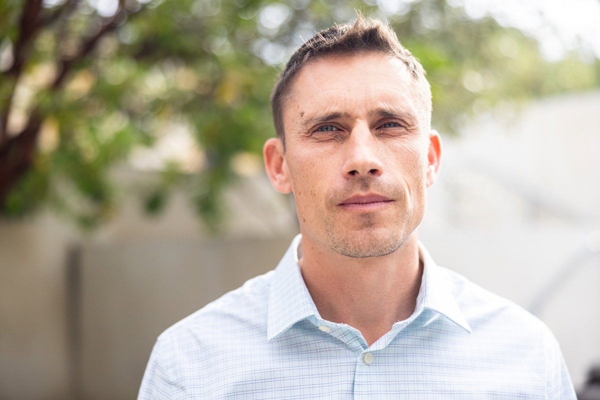 mężczyzna w wieku 30 plus w koszuli w krateczkę stoi na zewnątrz z poważnym spojrzeniem