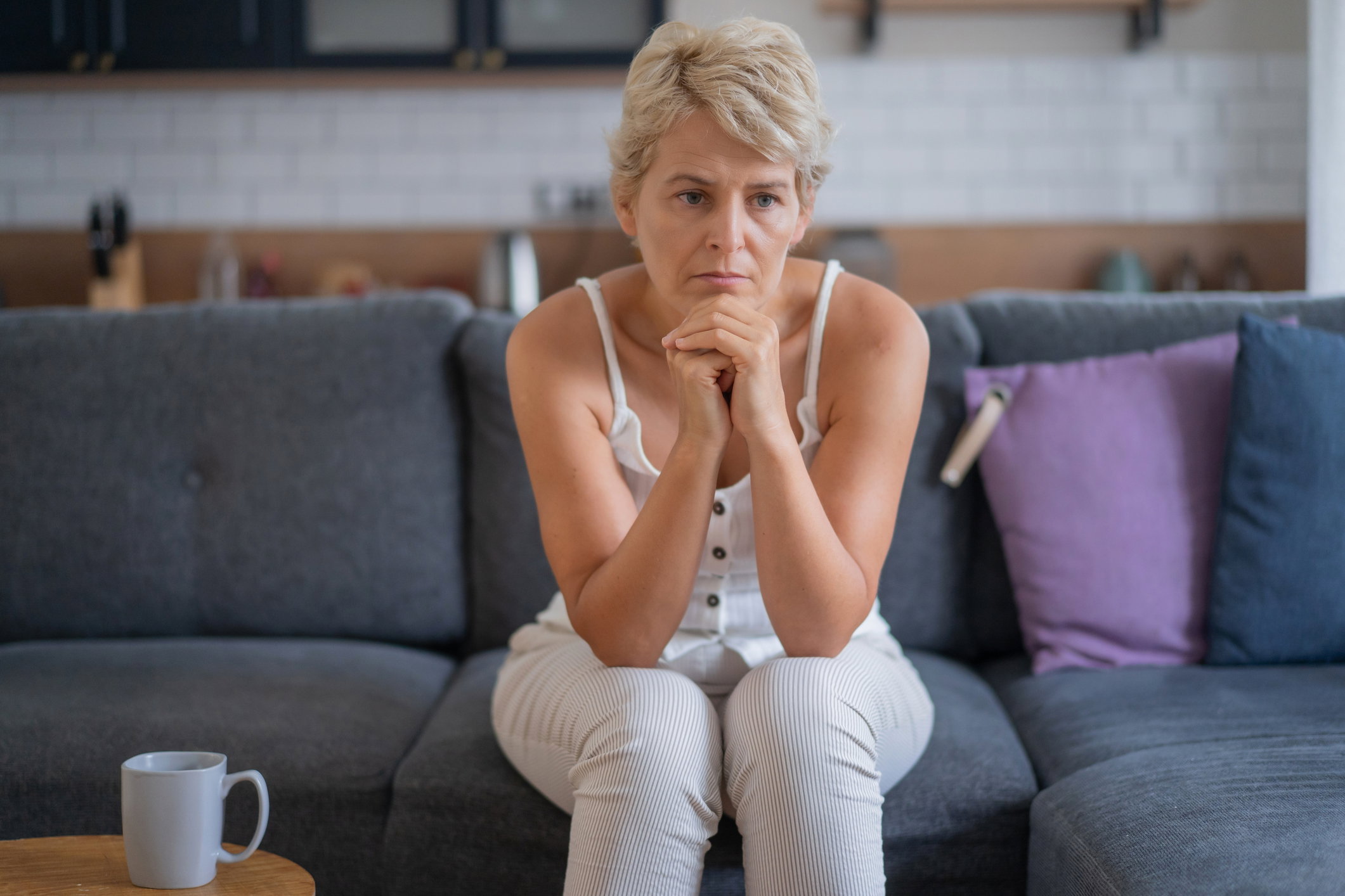 Woman looking thoughtful while sitting on the sofa at home