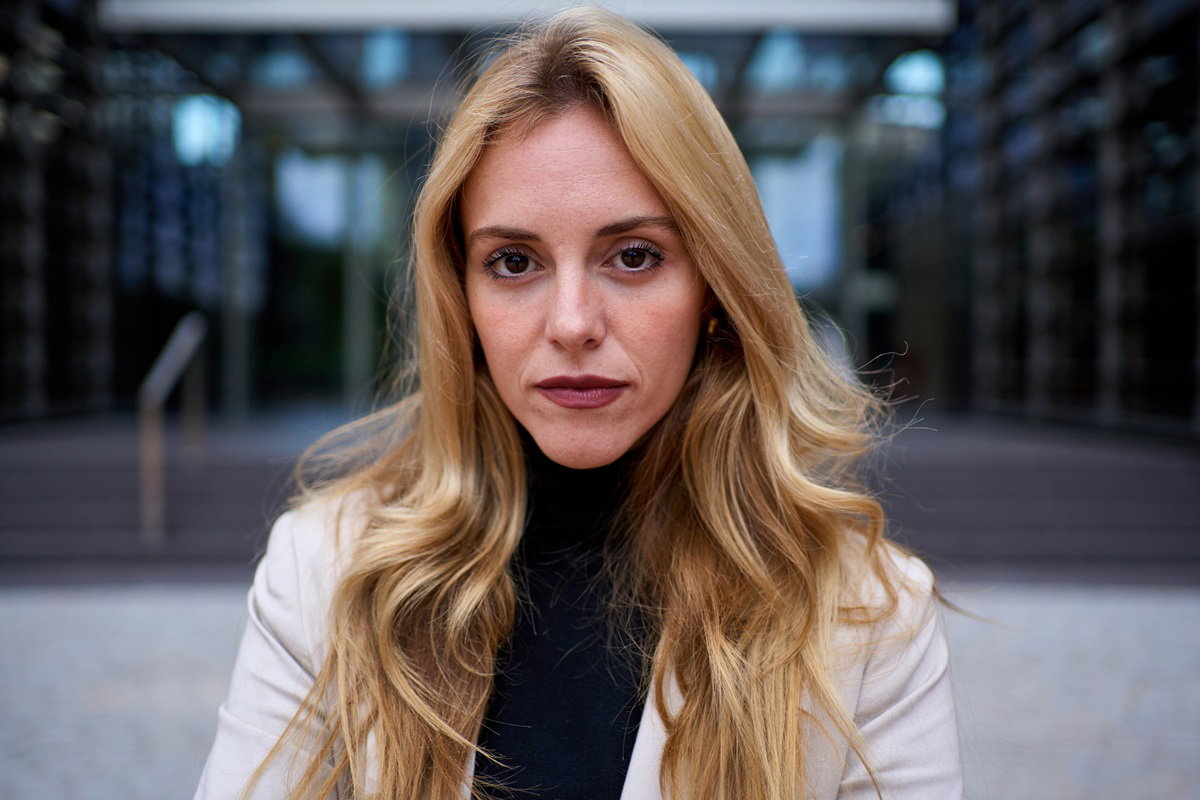 młoda kobieta blondynka stoi na tle budynku ze smutnym spojrzeniem