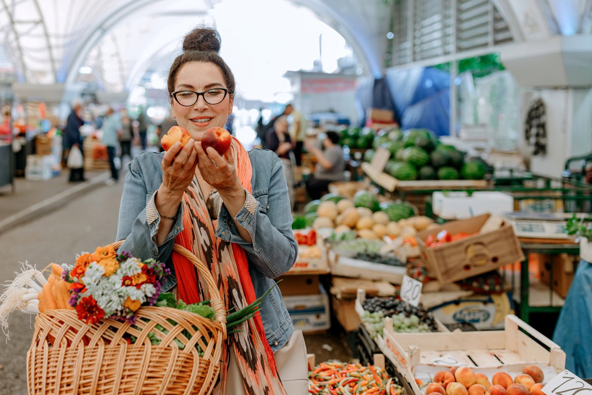 kobieta w okularach ogląda na targu dorodne brzoskwinie