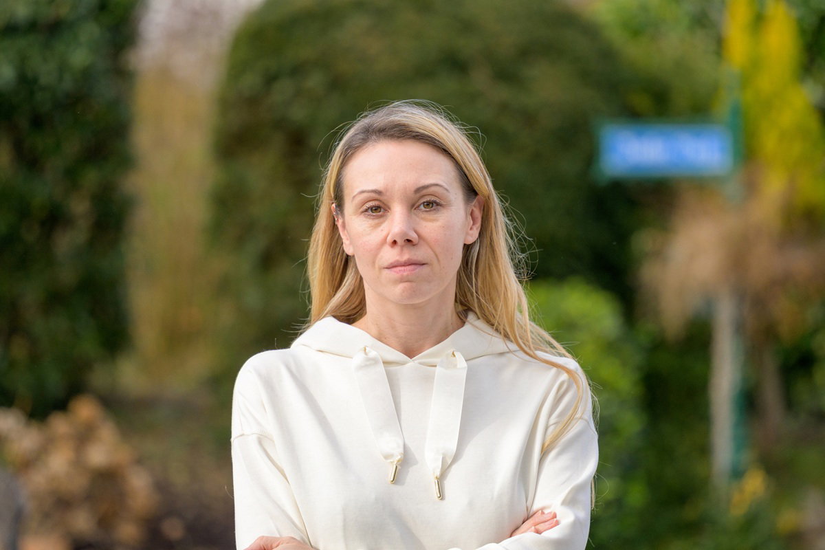 zmęczona kobieta około 35 plus blondynka stoi na zewnątrz w białej bluzie