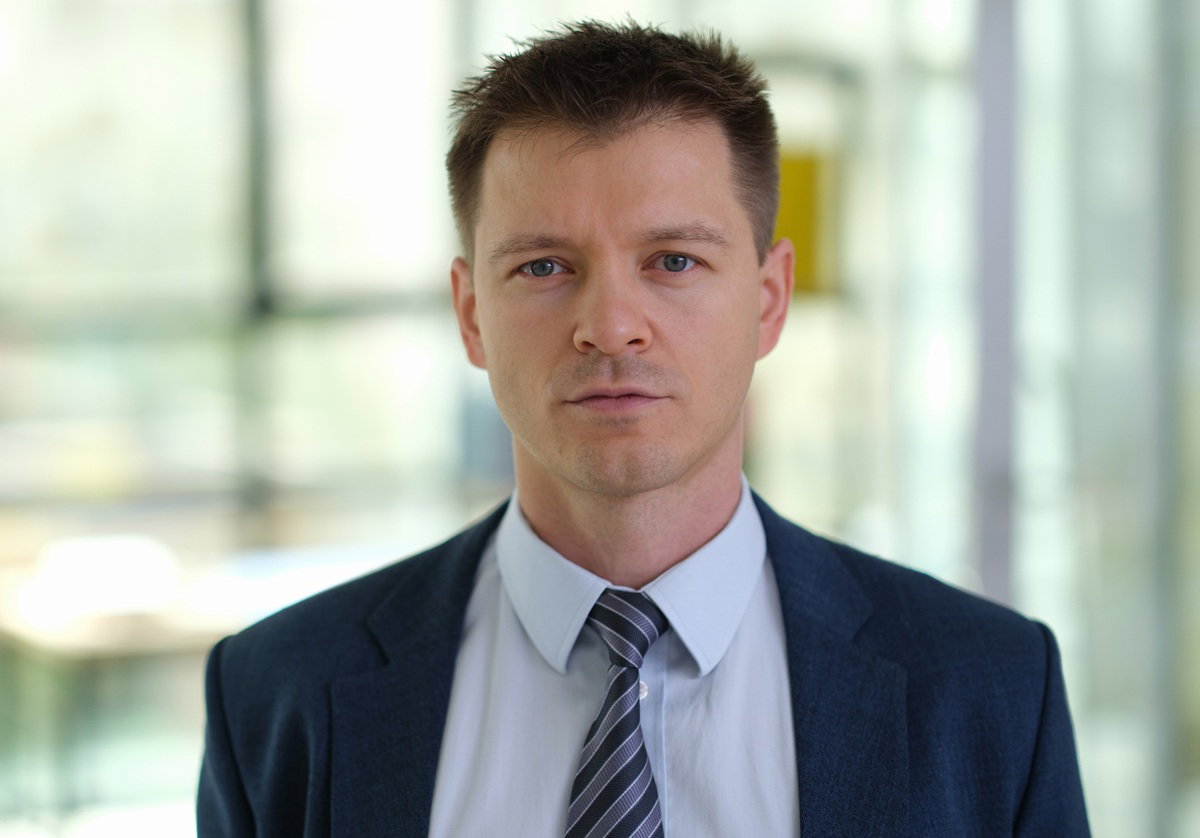 mężczyzna w wieku około 40 lat w garniturze stoi i patrzy poważnym wzrokiem