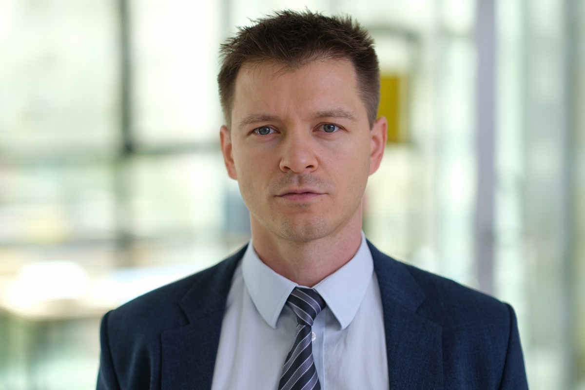 mężczyzna w wieku około 40 lat w garniturze stoi i patrzy poważnym wzrokiem