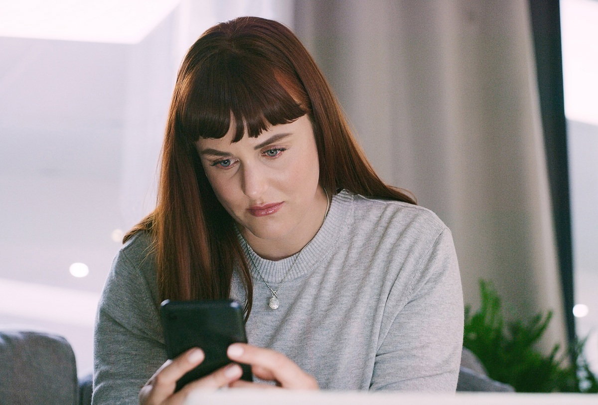 kobieta w wieku około 35 plus patrzy smutno w telefon