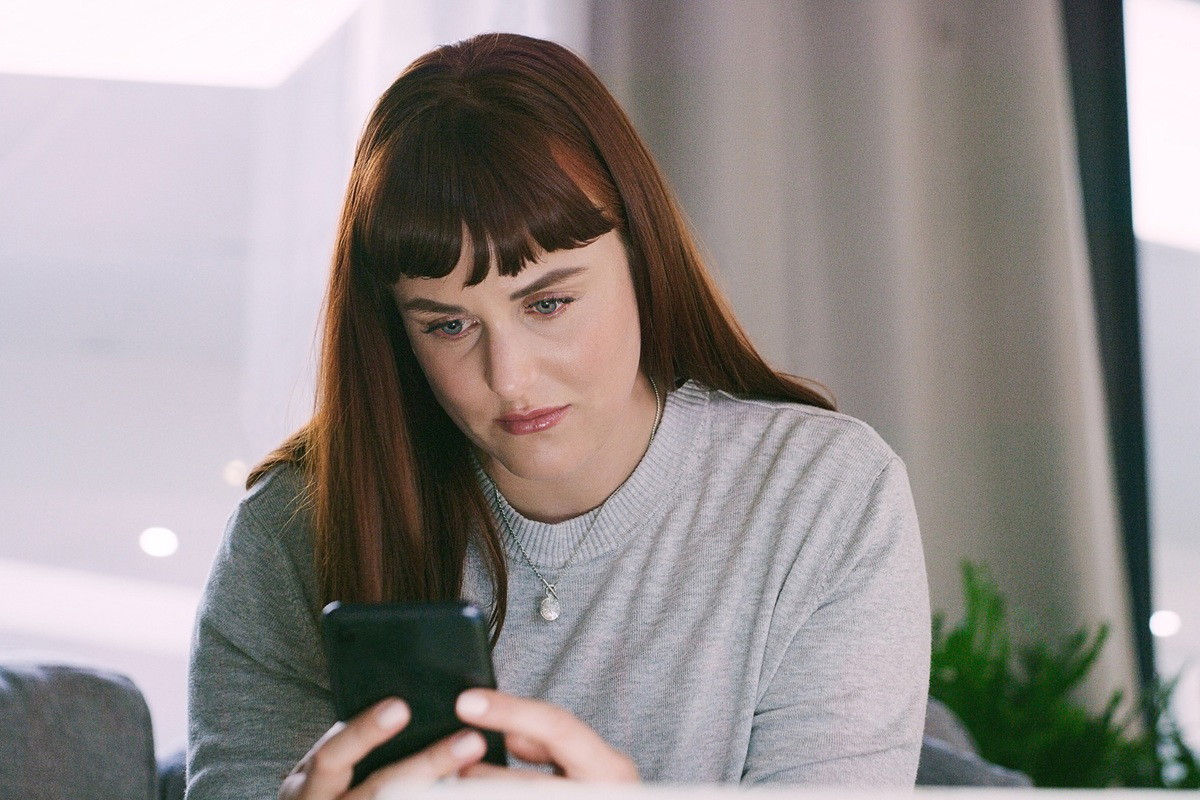 kobieta w wieku około 35 plus patrzy smutno w telefon