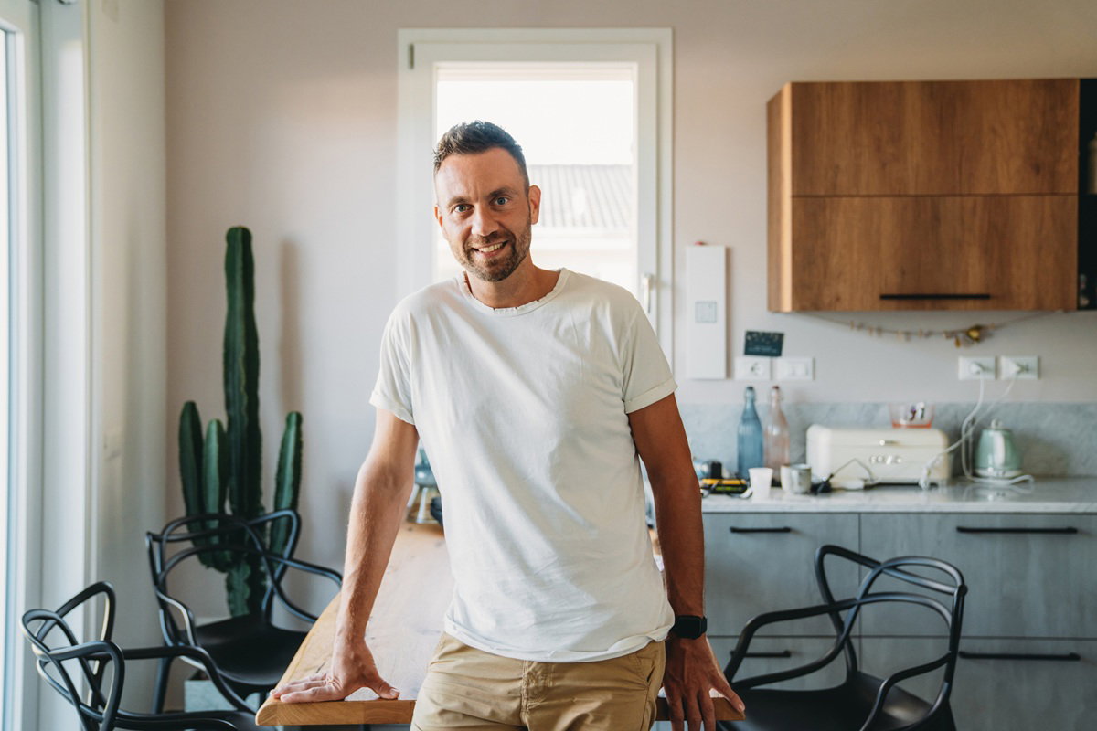 mężczyzna około 40 lat z zarostem stoi na tle kuchni i się uśmiecha